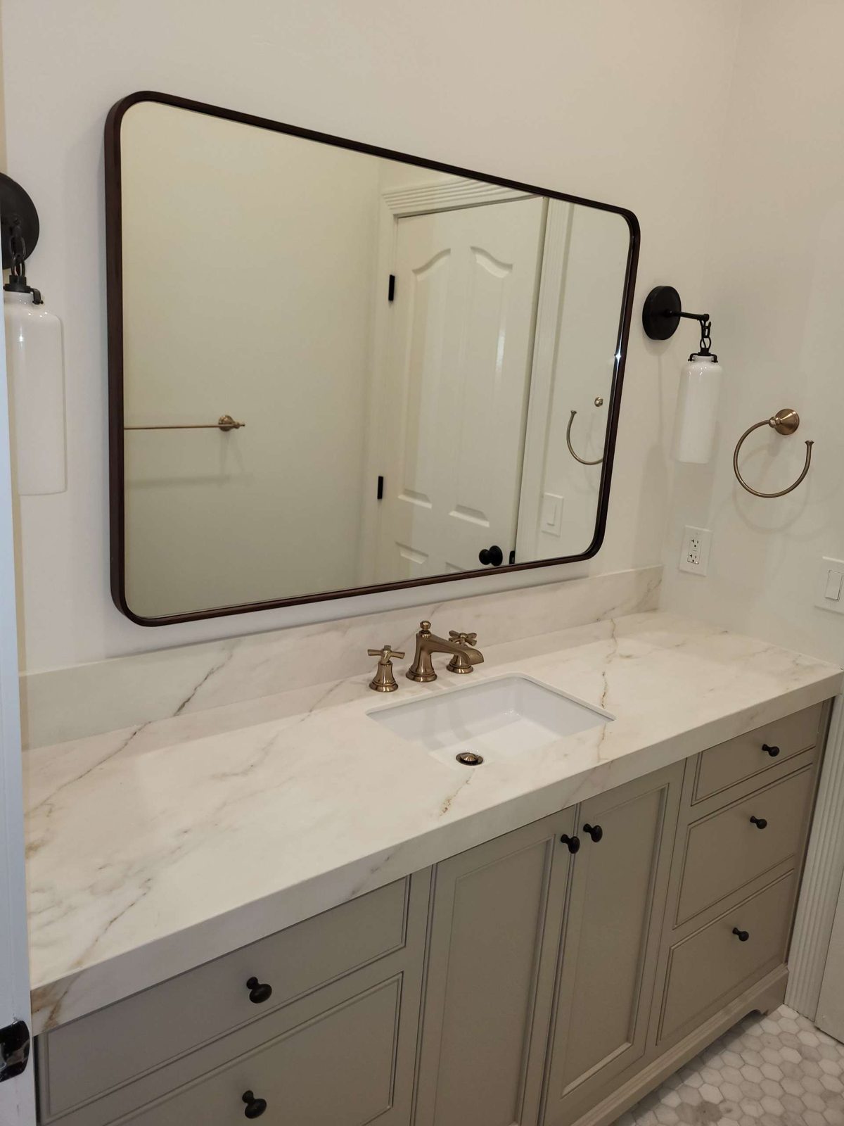 Finished bathroom vanity with marble counter and brass fixtures